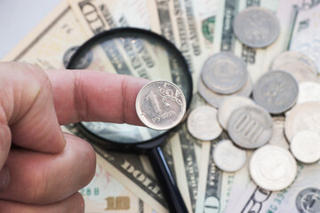 A one-ruble Russian coin is held on the finger.