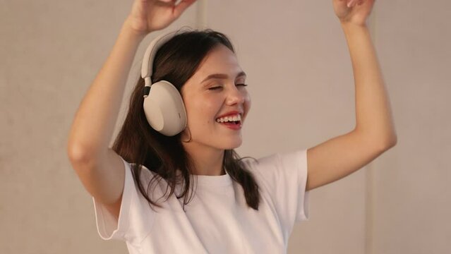 Closeup of a carefree teenager wearing noise-canceling headphones, dancing energetically to loud music, embracing the spirit of youthfulness