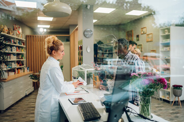Obraz premium Woman pharmacist selling drugs to a senior patient customer in a pharmacy