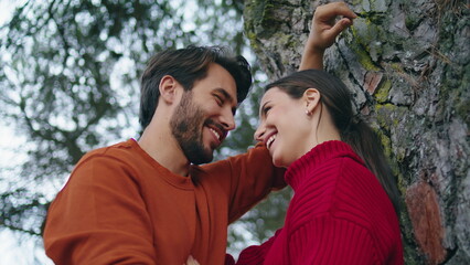 Happy smiling couple standing forest leaning on tree close up. Family laughing