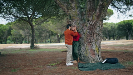 Fototapeta premium Loving couple enjoy weekend on nature. Happy tourists standing hugging near tree
