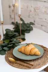 Croissant on a plate on a home or restaurant table. Exquisite decoration and serving. Decorated table.