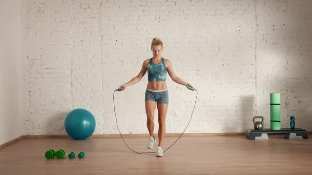 Healthcare and wellness advertisement concept. Athletic woman fitness coach doing classic jumps with skipping rope for classes.