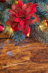 A festive Christmas garland featuring vibrant poinsettia flower beautifully displayed on a rustic wooden backdrop - 661176710
