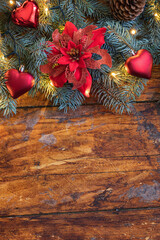 A festive Christmas garland featuring vibrant poinsettia flower beautifully displayed on a rustic wooden backdrop - 661176717