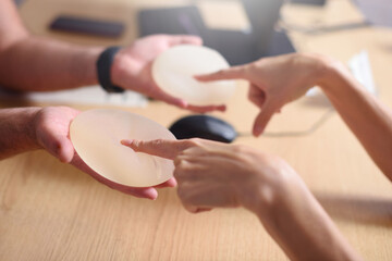 Female hand picks silicone implants for breast augmentation