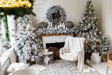 A soft chair covered with a plaid against the background of a New Year's fireplace decorated with Christmas trees, lights and candles