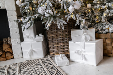 White gift boxes near a snowy Christmas tree and with a fairy-tale Christmas decoration.