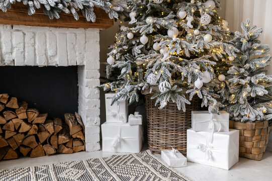 White gift boxes near a snowy Christmas tree and with a fairy-tale Christmas decoration.