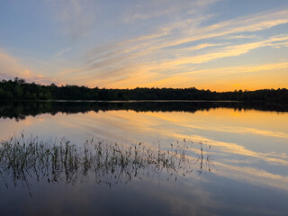 Sunset over fresh water lake with reeds in foreground
