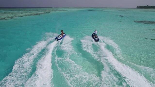 A couple rides jetskis in the Maldives