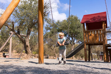 a little boy of three years old, blond, plays on the playground