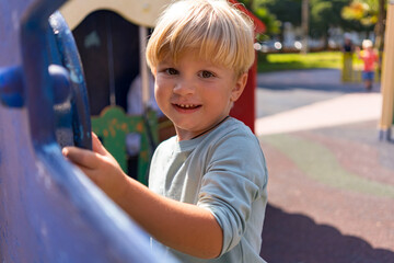 a blond boy of three years old plays on the playground