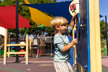 a blond boy of three years old plays on the playground