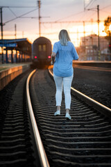 woman running on railroad  to catch a train during sunset 