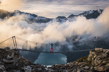 woman standing on Schlegeisspeicher bridge with fog over lake during sunrise 