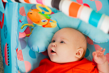 Portrait of a cute little baby boy lying in the playroom