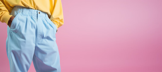 Close-up of legs in baggy street style jeans isolated on flat pastel background with copy space, cropped image. Creative concept of street style youth clothing. Pink blue colors banner. 