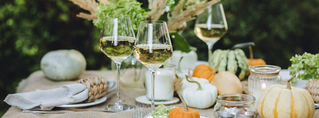 Simple craft elements, pumpkins as decoration, candles. Lunch outdoors in the garden. Cozy dinner table decor for an autumn event, countryside party, thanksgiving dinner or wedding banner