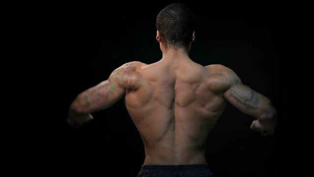 Man posing on a black background, shows his muscles