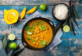 Traditional Indian vegetarian curry stew with sweet potatoes, pumpkin and rice served as top view in saucepan