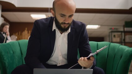 Business investor reads notes on files working on laptop before starting official conference, hotel...