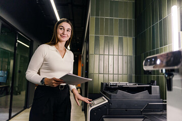 A confident employee of the company uses a printer and paper. A freelancer smiles at an online...