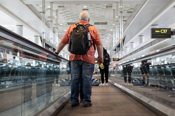 man with backpack on airport moving walkway