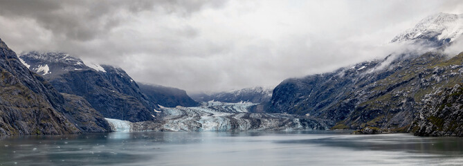 panorama of glacier with clouds, mist rocks and ice