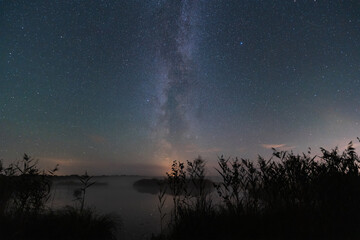 Night landscape in Estonia, the milky way and the starry sky over the lake set in autumn.