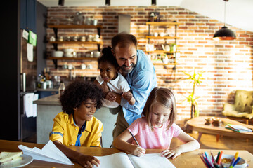 Young father helping his mixed children with homework at home