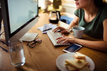 Close up of a young woman typing on a computer keyboard at home