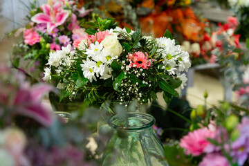 Bouquets of flowers in glassy vases in showroom of floral shop.