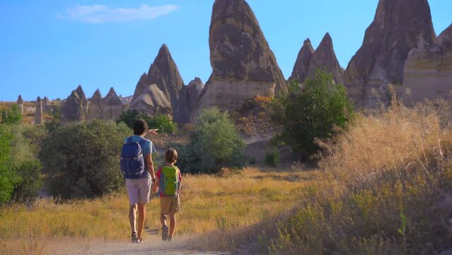 A young man and his son tourists visits the Love Valley in Cappadocia, Turkey, where nature's artistry has carved a surreal landscape of distinct-shaped rocks. These unique formations, shaped by
