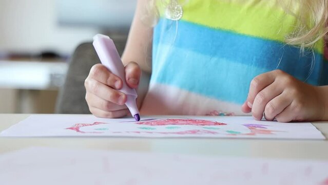Little girl draws on paper.
