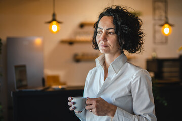 Mature woman having cup of coffee at home or office in morning