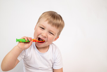 Little boy with a toothbrush on a white background carefully brushes his teeth close-up portrait. the concept of caring for children's milk teeth, personal hygiene procedure.