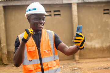 excited young african engineer checking his phone rejoices