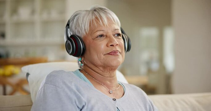 Happy woman, senior and music headphones in home for listening to audio, radio and podcast on sofa. Elderly lady thinking of peace while streaming sound, multimedia and subscription in living room