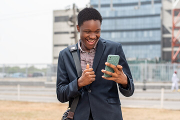 young african man checks phone and looks surprised