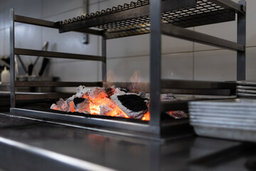 Grill of a professional kitchen preparing the fire to start the service.