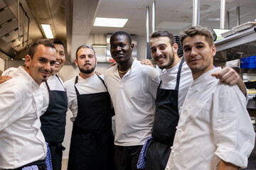Multi racial cooking team posing for a team photo in the kitchen at work
