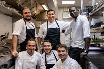 Multi ethnic cooking team posing for a team photo in the kitchen at work - Powered by Adobe