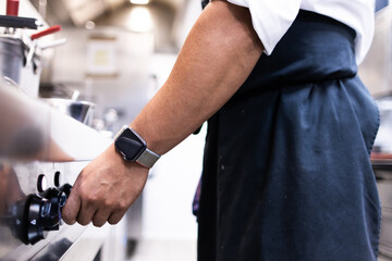 Hand with smart watch in a restaurant kitchen lighting the stove to start cooking