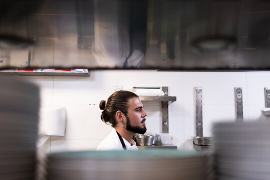 Side photo of the face of a chef with long hair in the restaurant kitchen