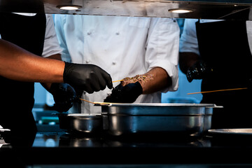 Photo of several hands with gloves preparing meat skewers in the restaurant