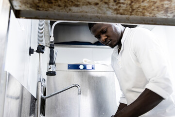 Black man cleaning dishes at his job in the kitchen cleaning area