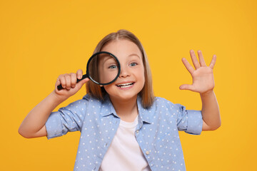 Cute little girl looking through magnifier on yellow background - obrazy, fototapety, plakaty