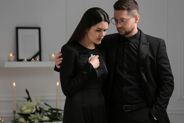 Sad couple mourning in room. Funeral ceremony