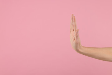 Woman showing stop gesture on pink background, closeup. Space for text